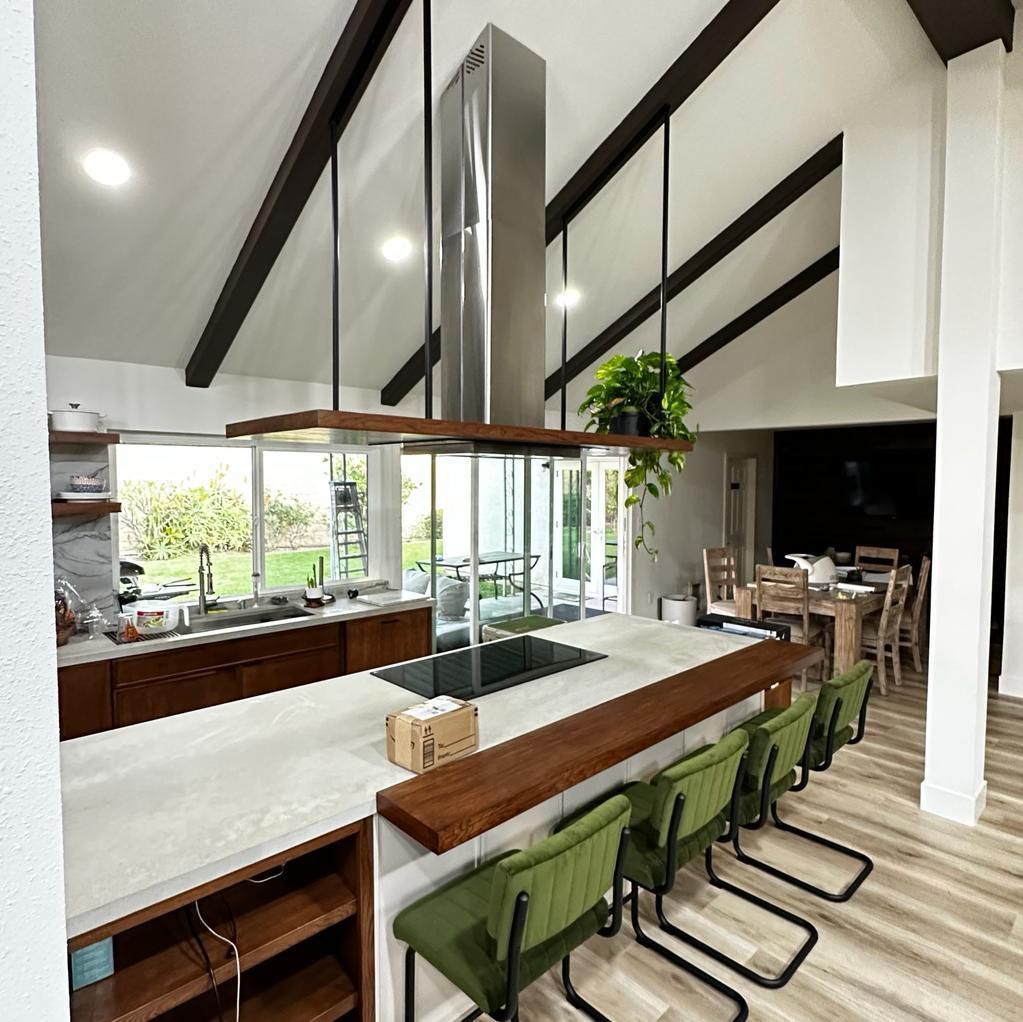 Modern kitchen with island, seating, dark wood cabinets, and high ceiling with beams.