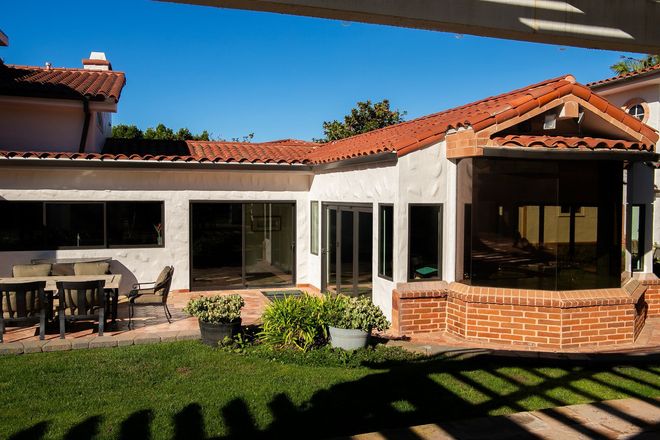 Two workers installing electrical wiring inside a wood-framed building under construction.