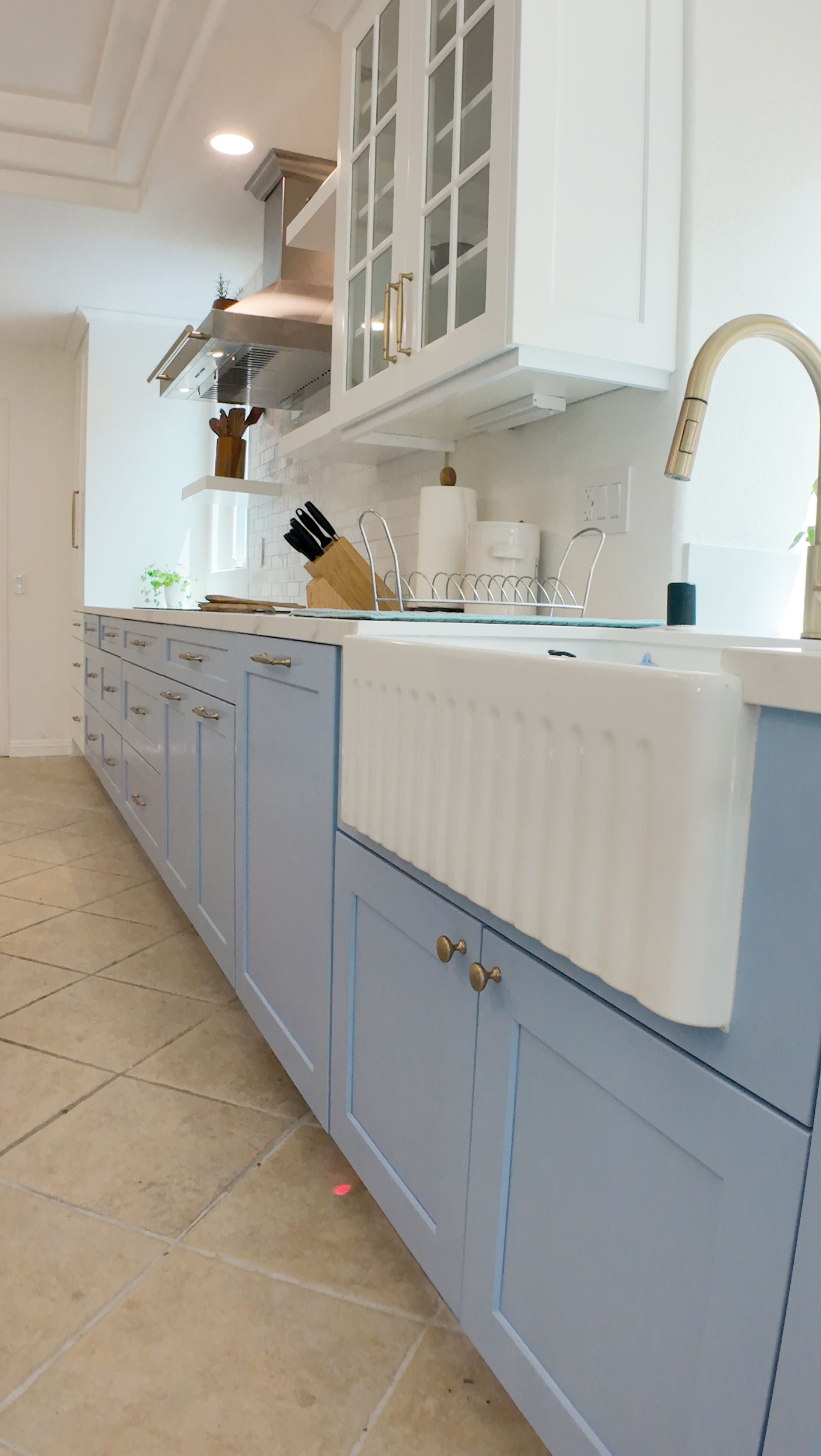 Light blue and white kitchen with a farmhouse sink and tile backsplash.