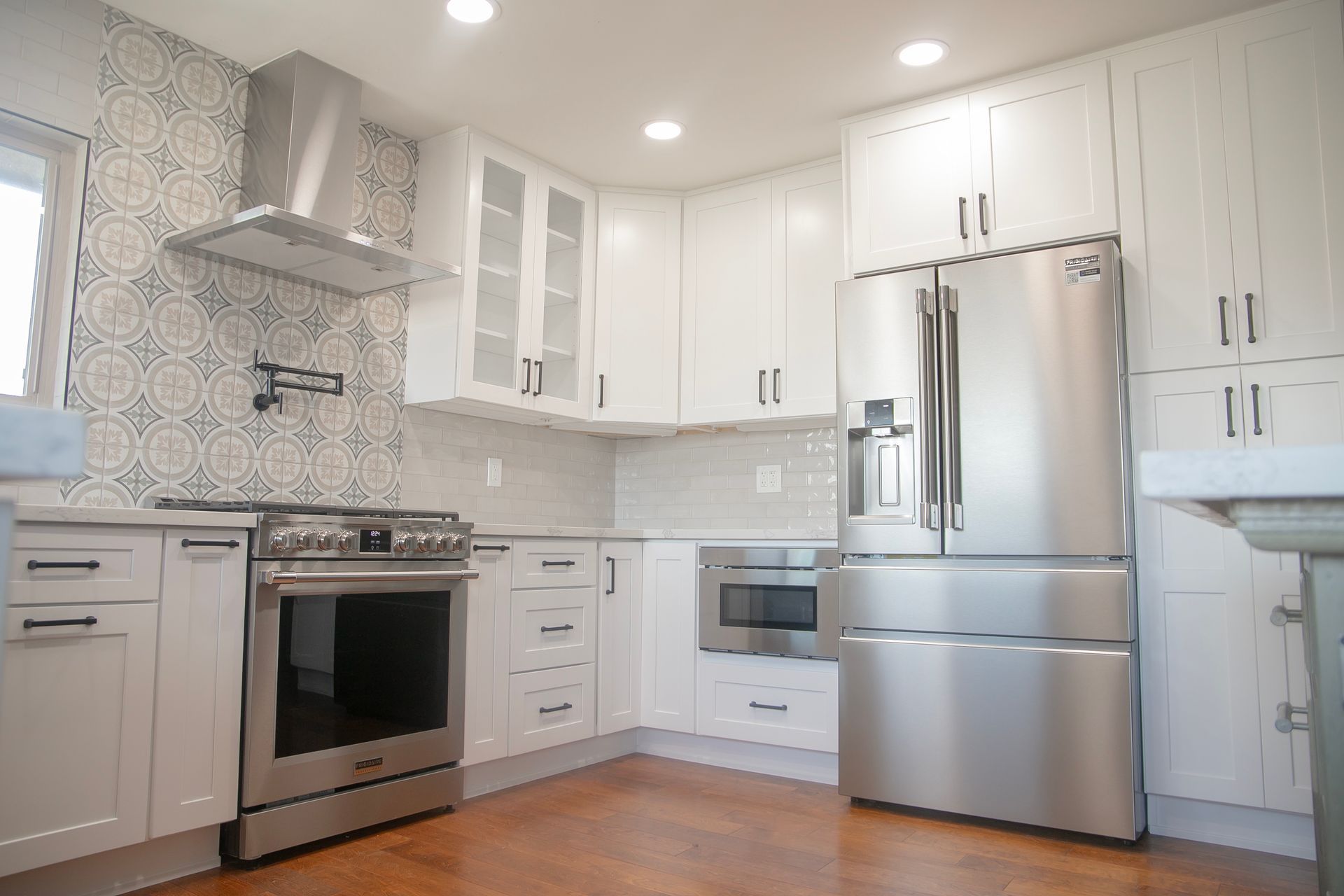 White kitchen with stainless steel appliances and patterned backsplash.