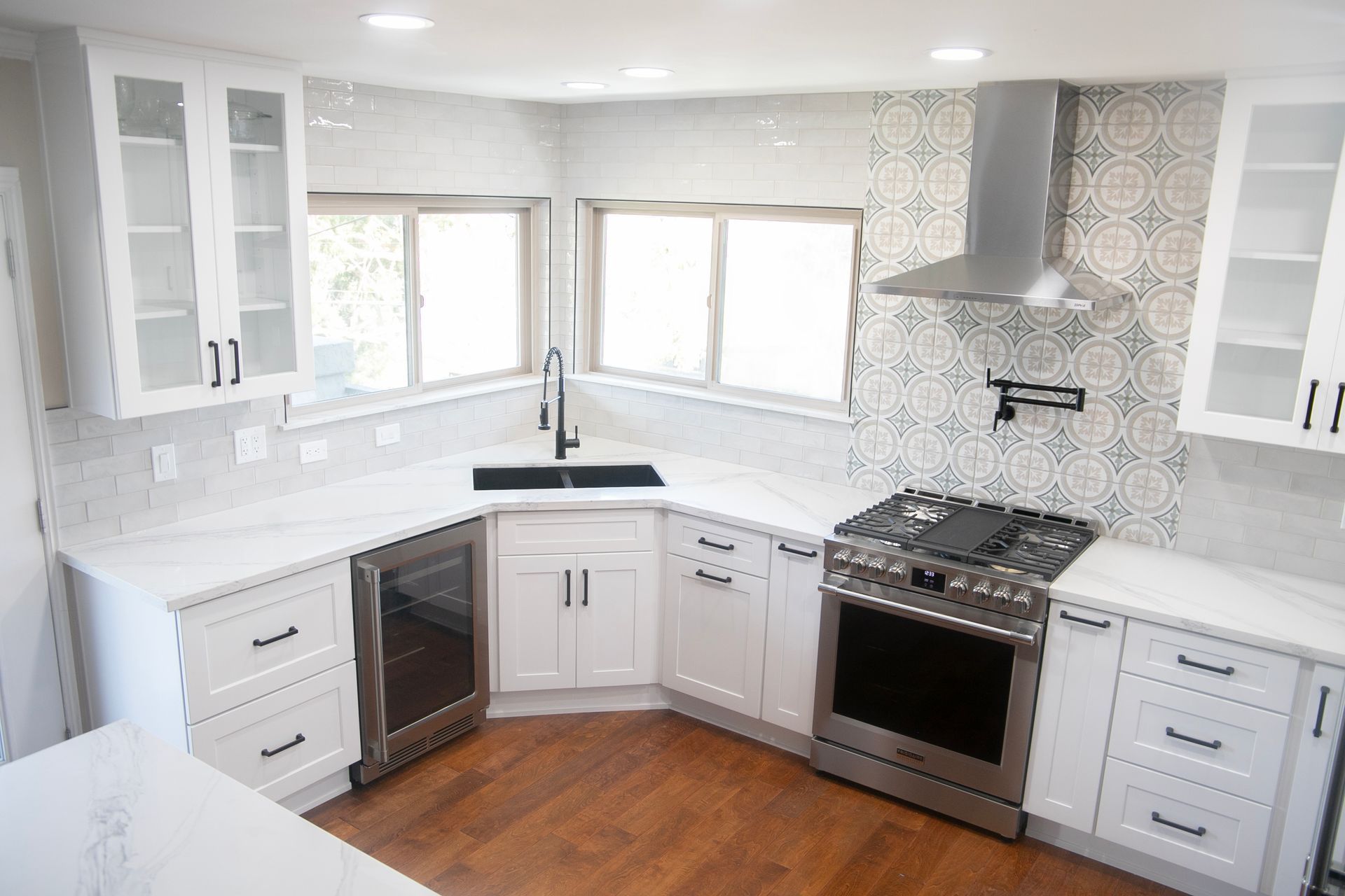 White kitchen with stainless steel appliances, white cabinets, and patterned backsplash.