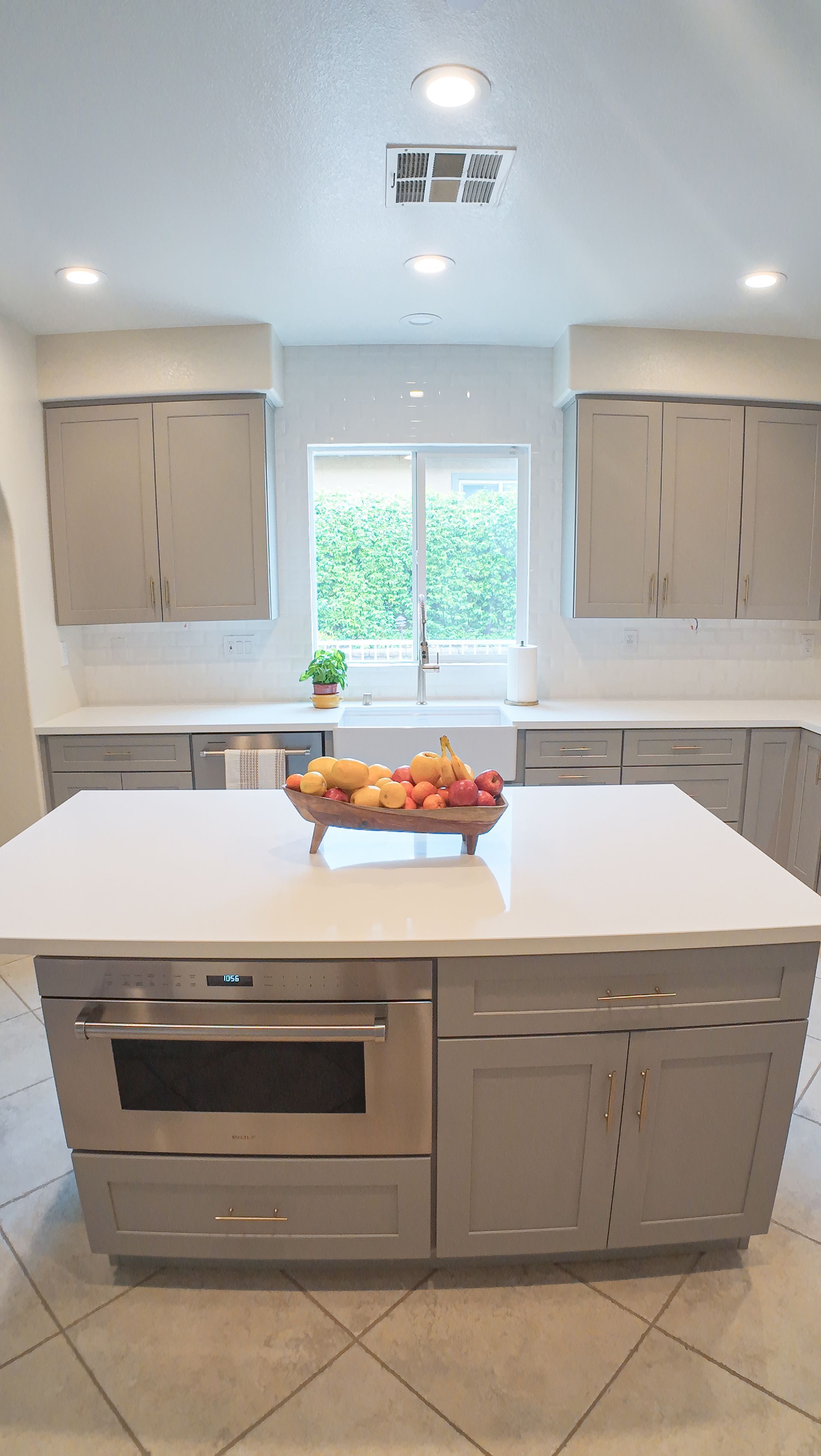 Modern kitchen with gray cabinets, white countertops, and a central island with a microwave.