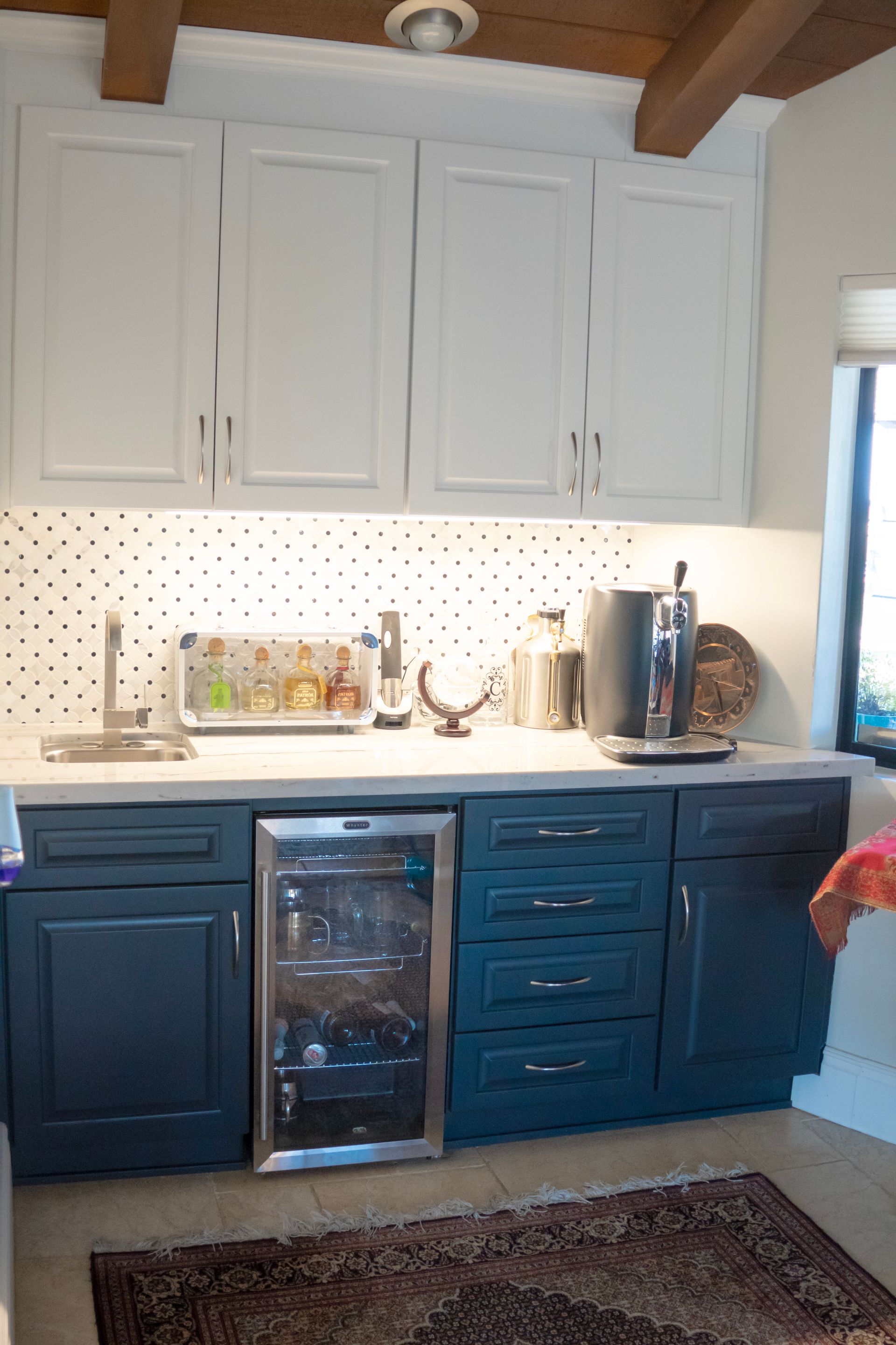 Kitchen bar with white upper cabinets, blue lower cabinets, and wine cooler.
