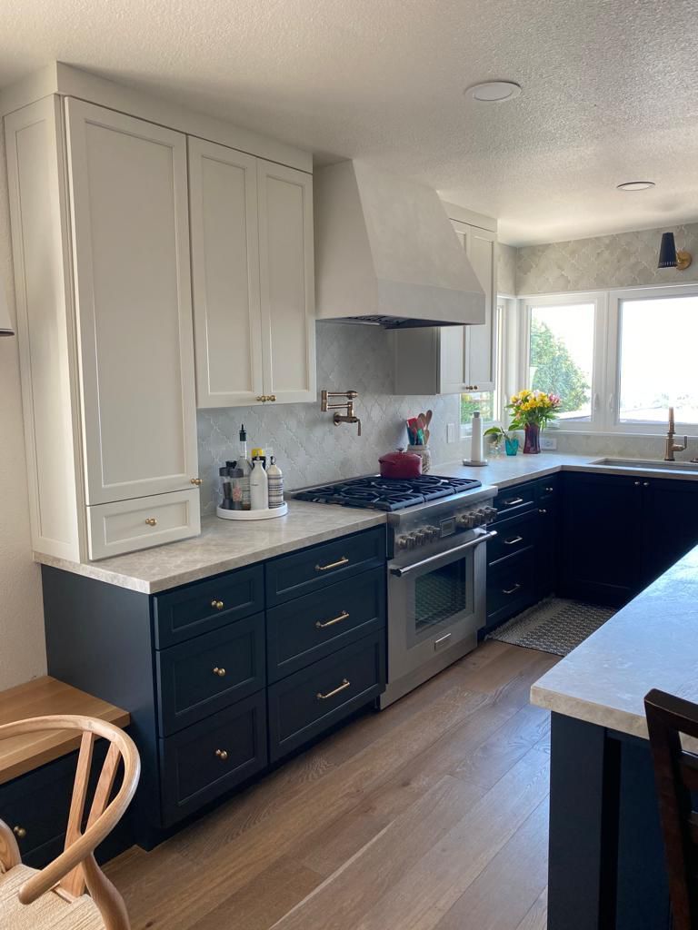 Two-tone kitchen with navy lower cabinets, white upper cabinets, and stainless steel range.