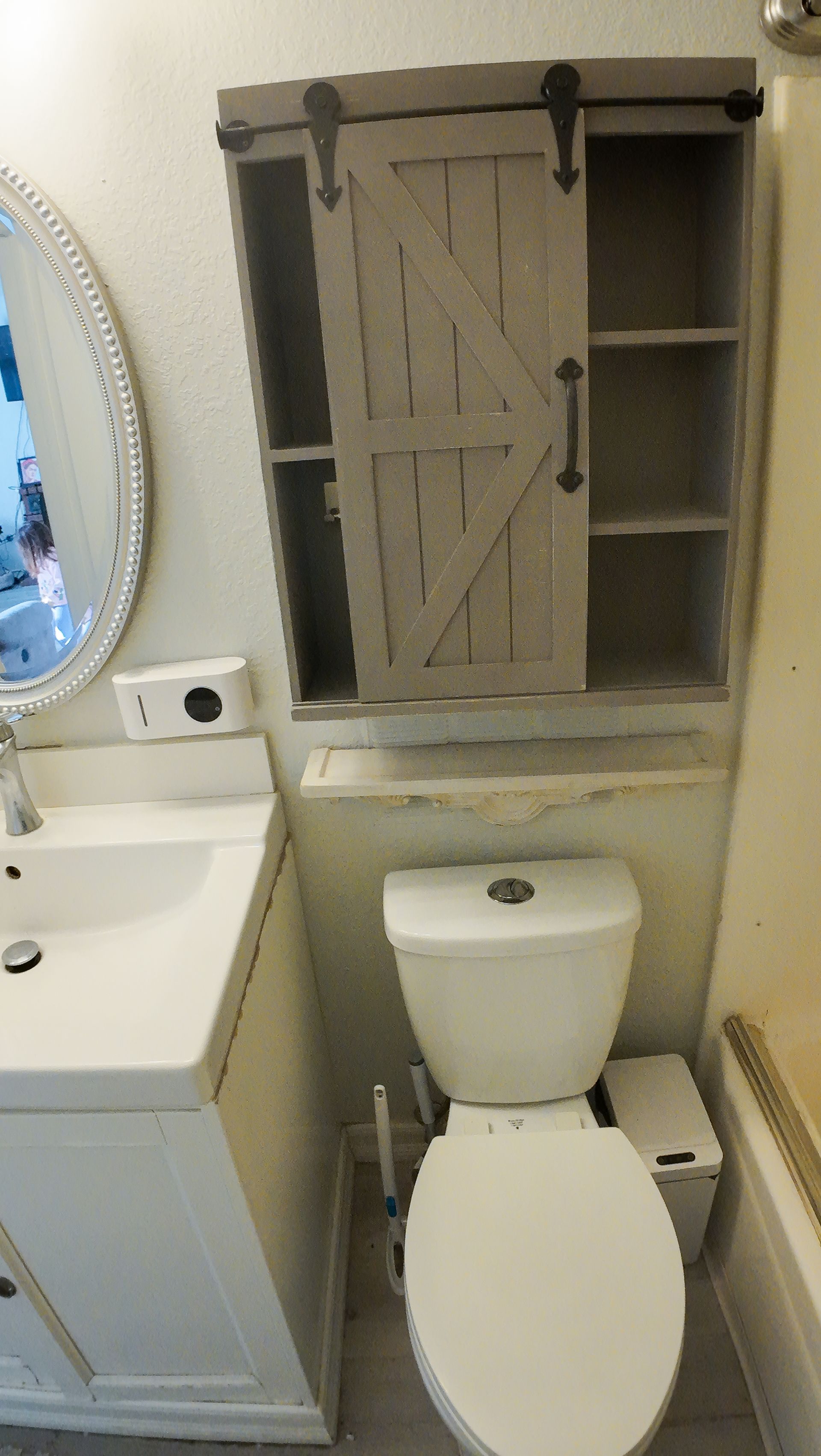 Bathroom with a white sink, toilet, and a gray cabinet with a sliding barn door.