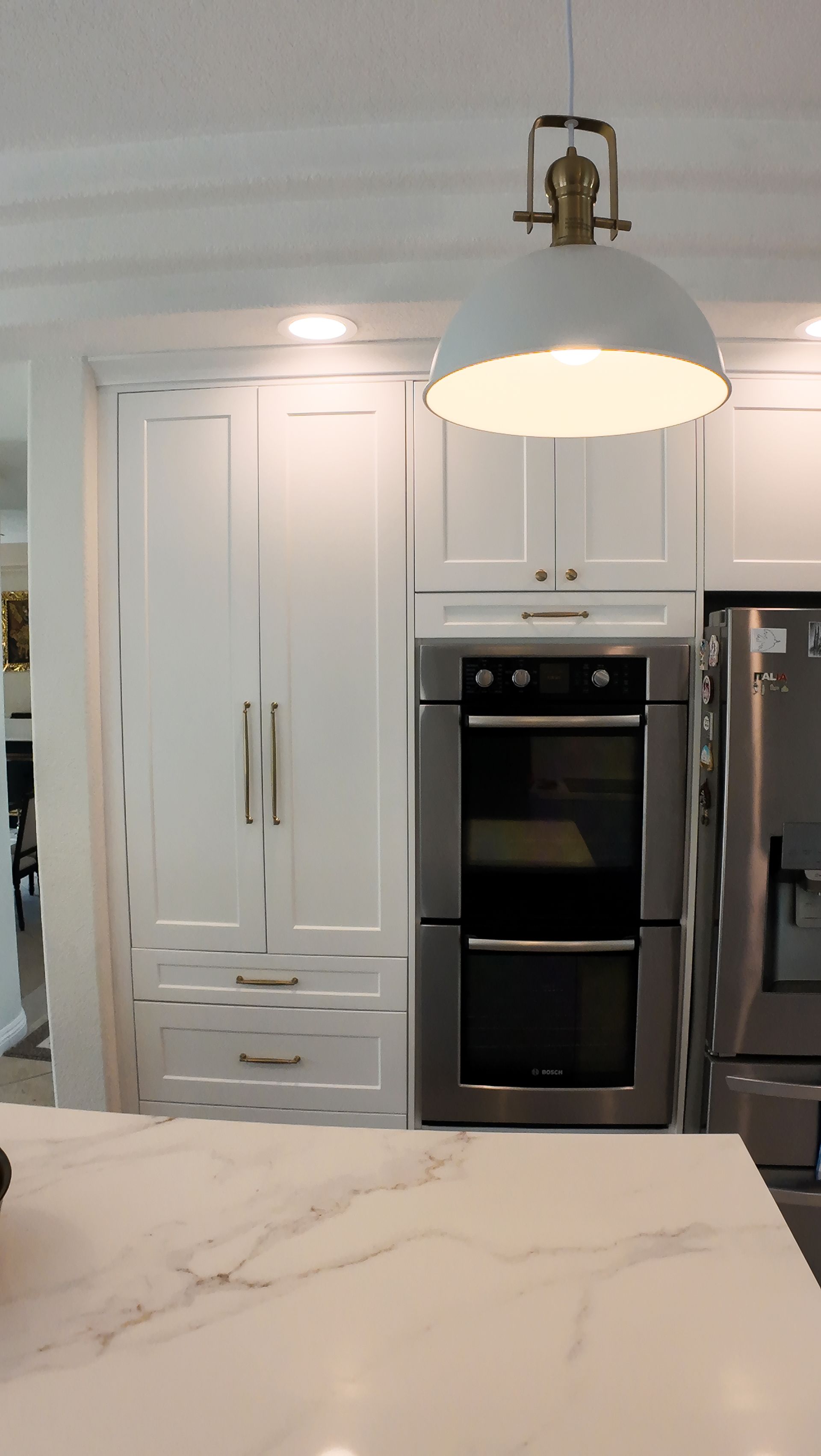 White kitchen cabinets and oven with a light fixture hanging overhead.