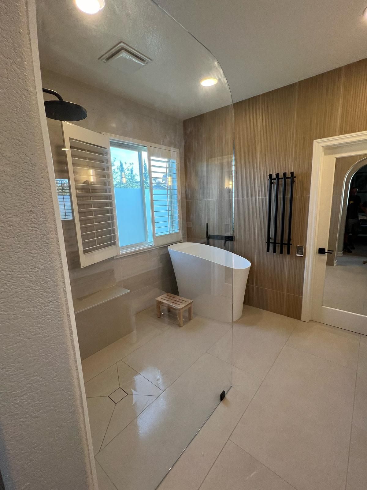 Modern bathroom with a white tub, shower, and tan tile walls.