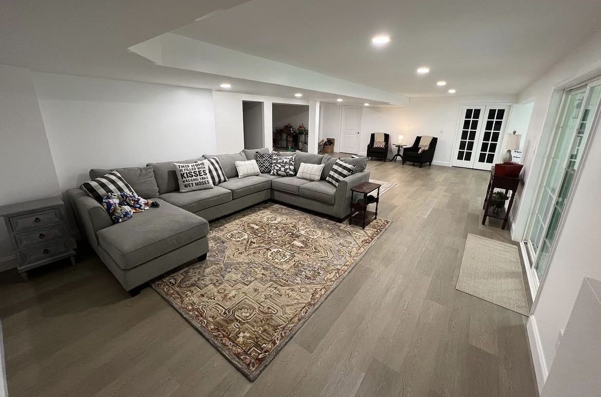 Spacious living room with a gray sectional, a patterned rug, and large windows.