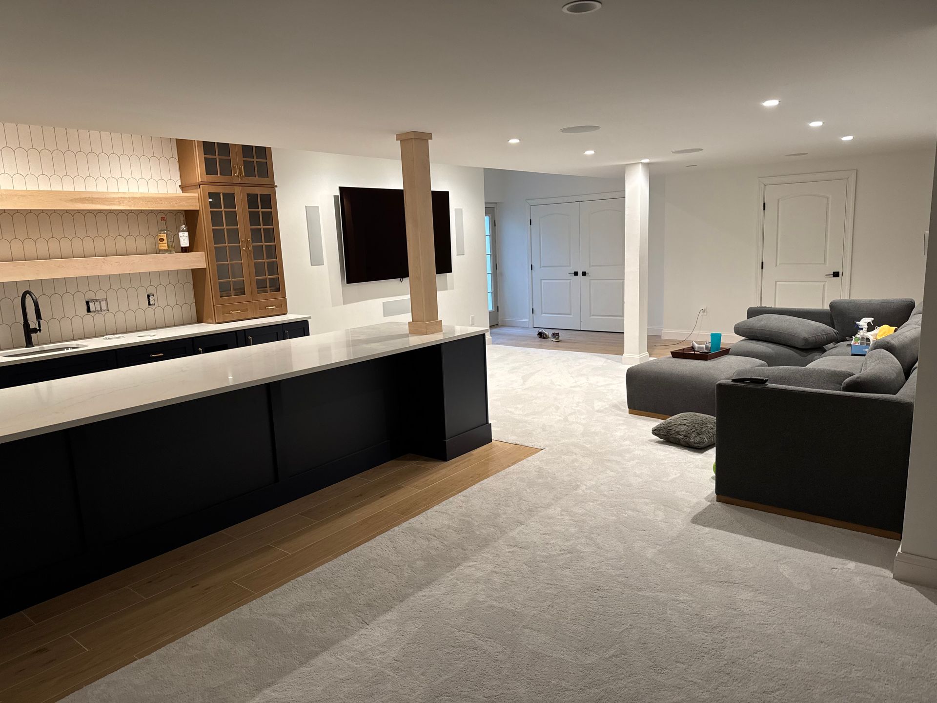 A finished basement with a kitchen area, living space, and a dark-colored island.