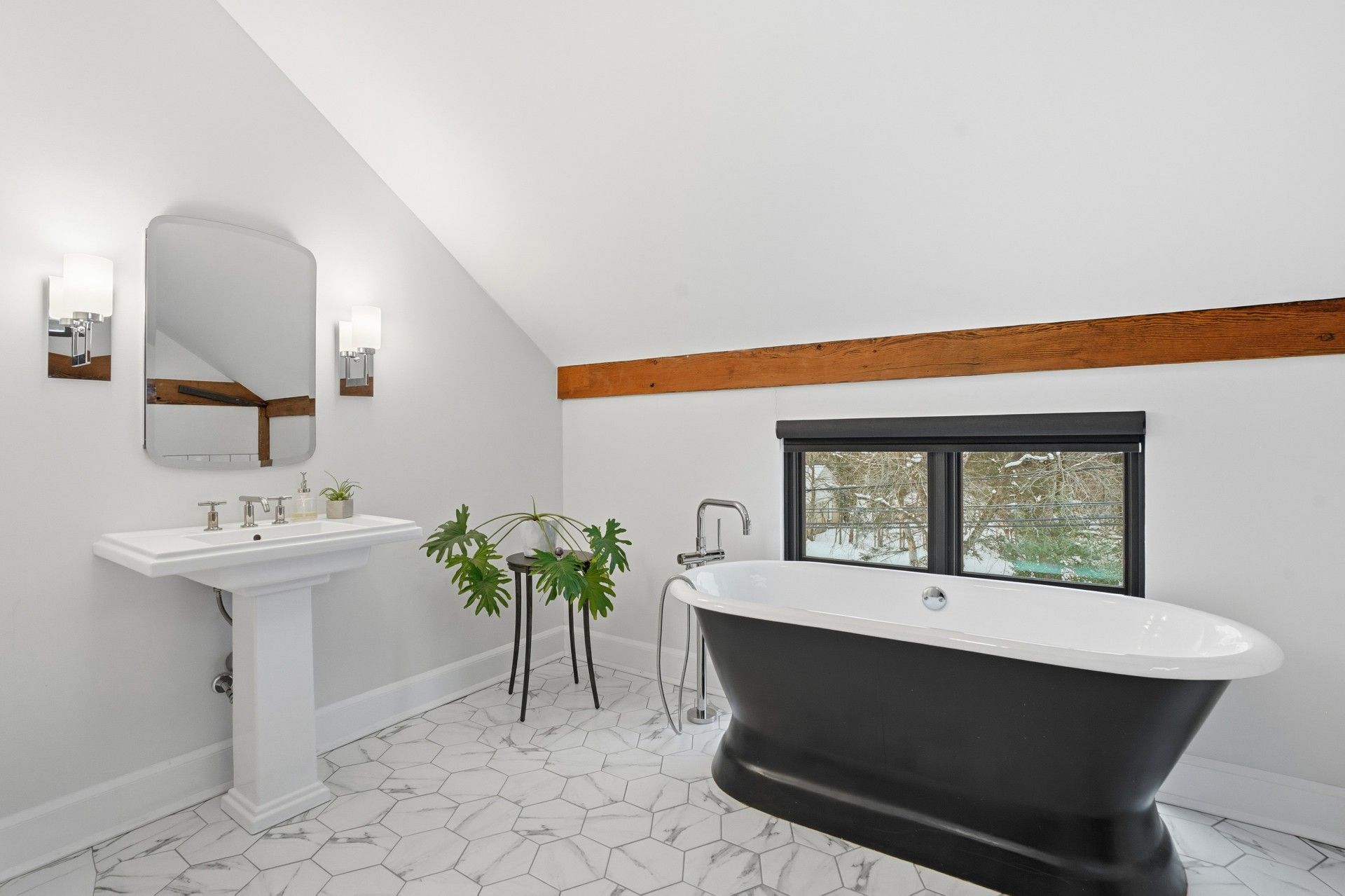 Bathroom with black freestanding tub, pedestal sink, and marble tile floor.