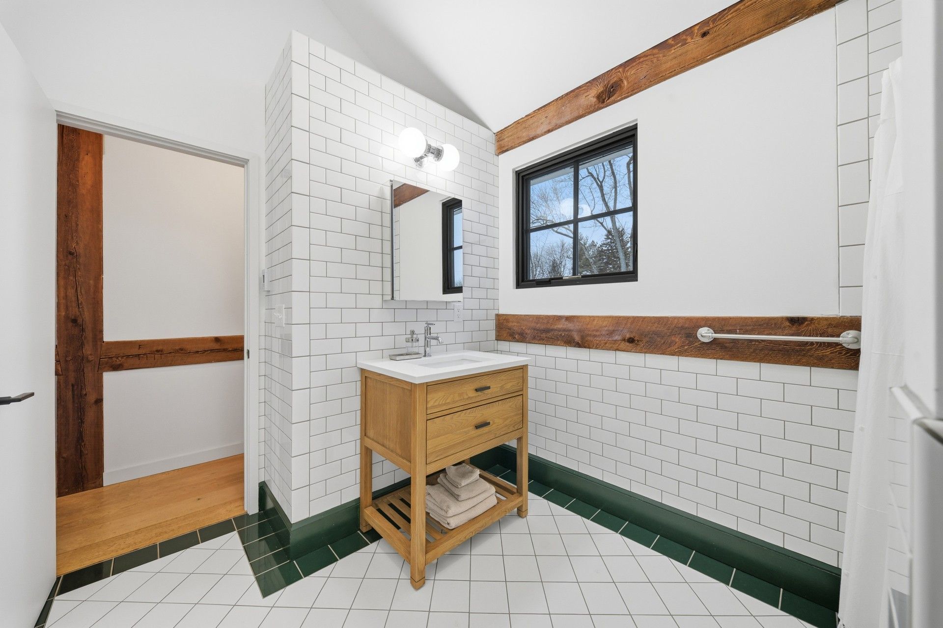 Bathroom with white brick tile, wooden vanity, and exposed beams.