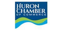 Logo for the Huron Chamber of Commerce featuring white text on a blue background above green and blue wave graphics.