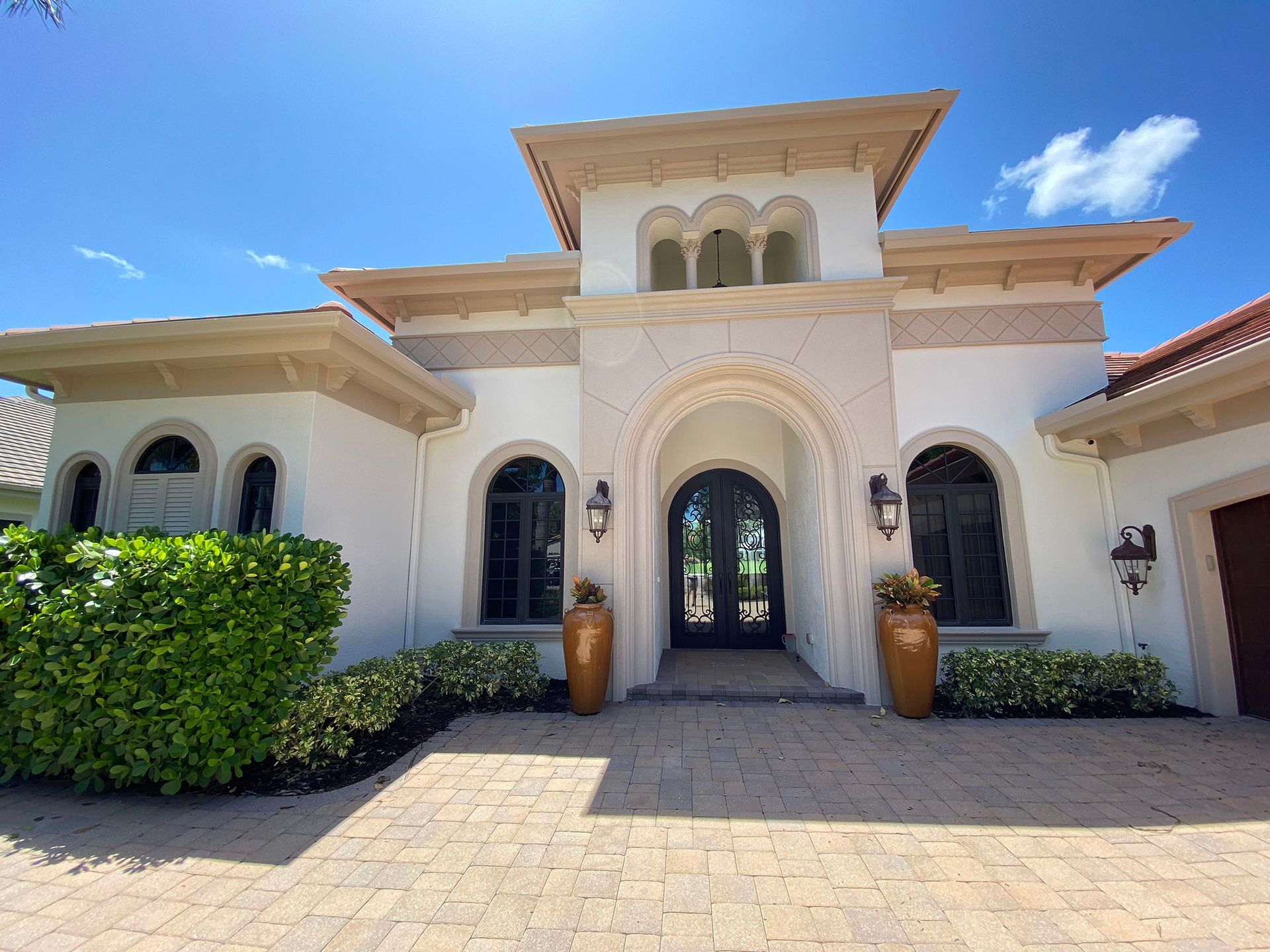 A large white house with a brick driveway in front of it.