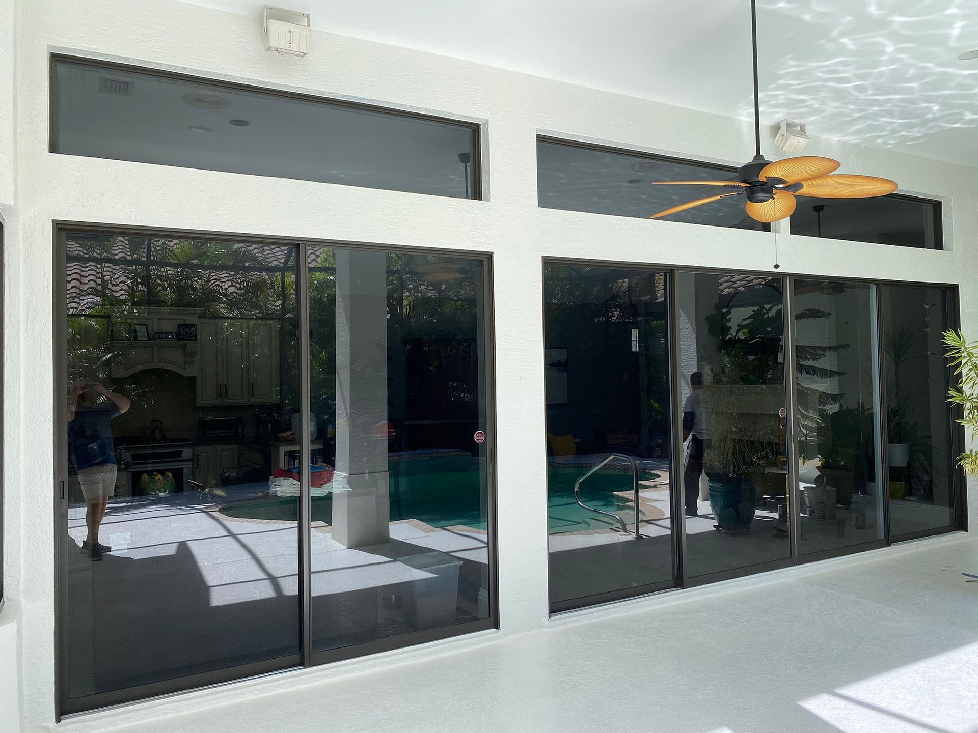 There is a ceiling fan hanging from the ceiling above the sliding glass doors.