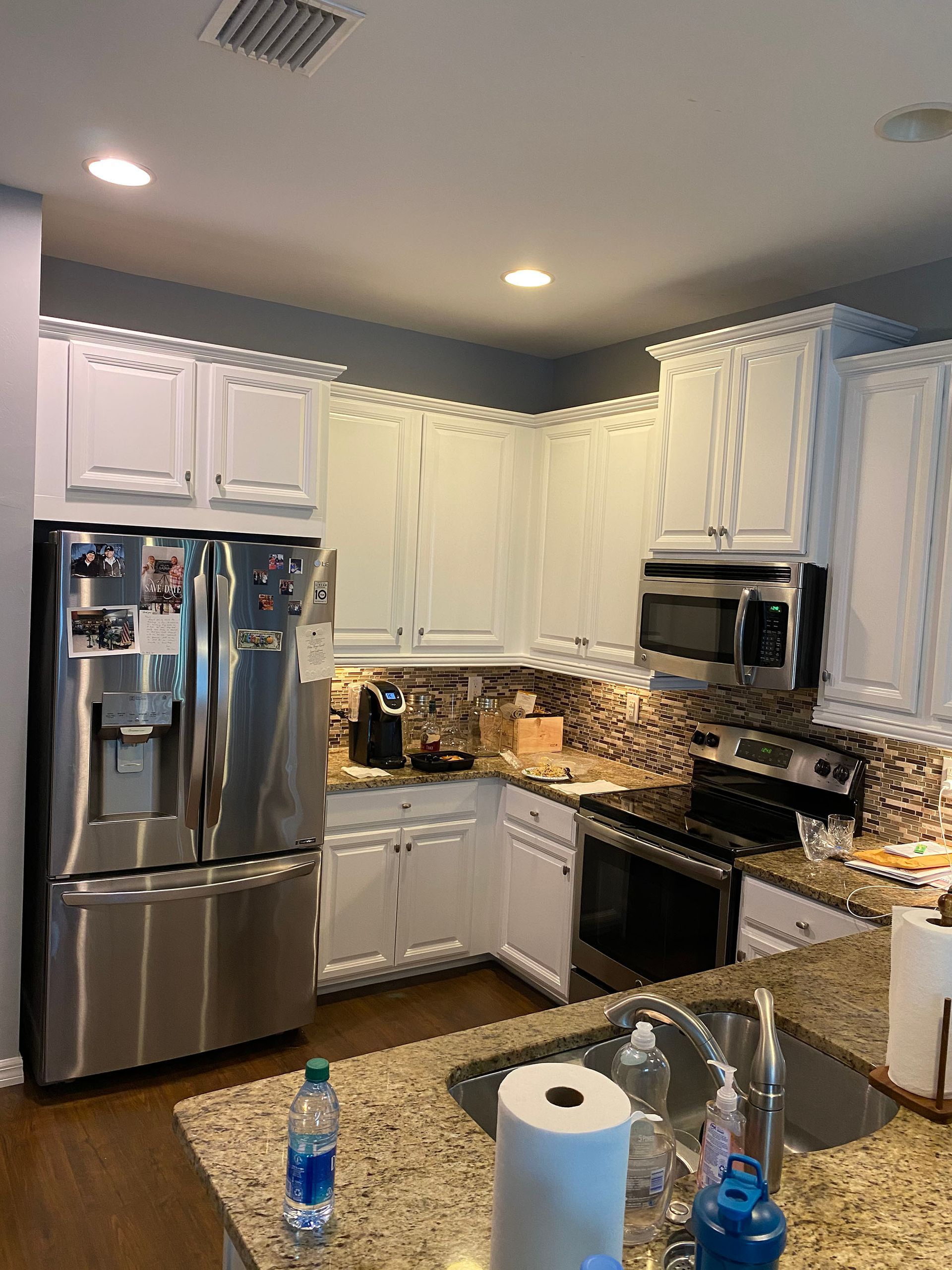 A kitchen with stainless steel appliances and white cabinets.