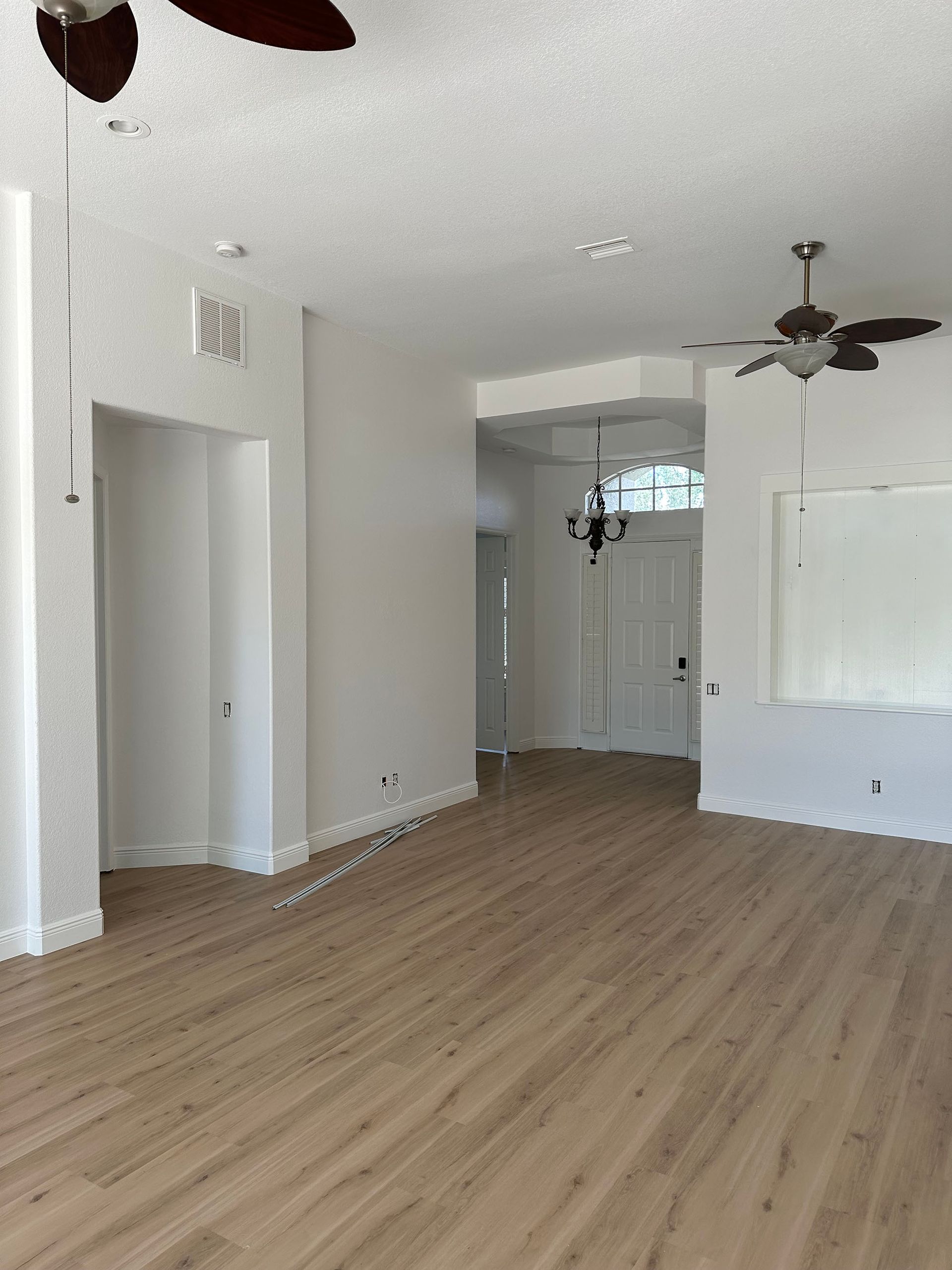 An empty living room with hardwood floors and a ceiling fan.