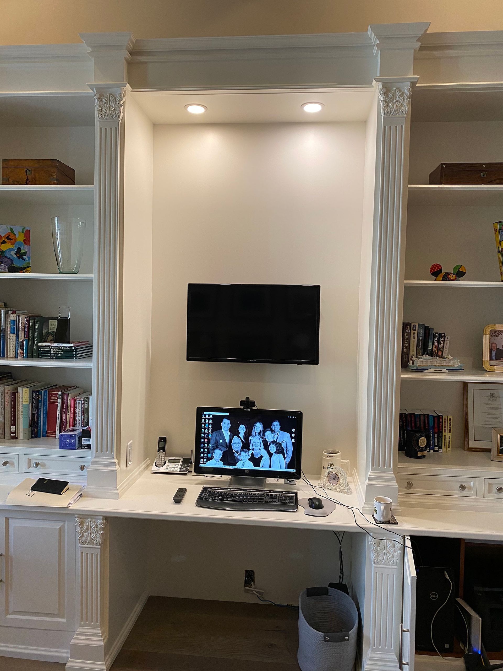 There is a desk with a computer and a television on the wall.