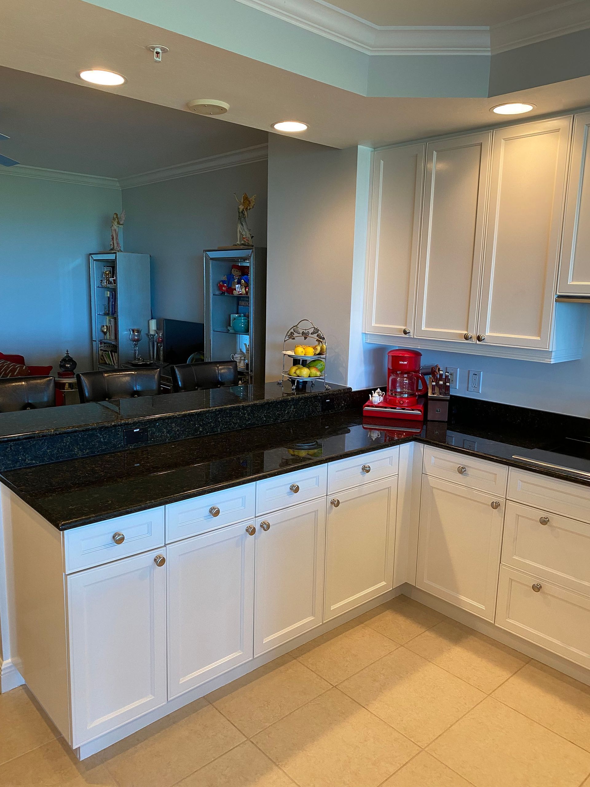 A kitchen with white cabinets and black counter tops.