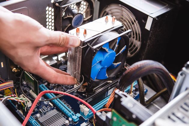 Hand installing a CPU cooler inside a desktop computer, with blue fan and exposed cables
