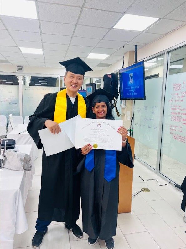 A man in a graduation cap and gown stands next to a woman holding a certificate