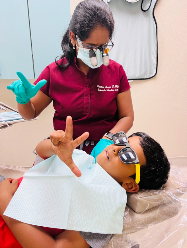 A young boy wearing sunglasses is laying in a dental chair