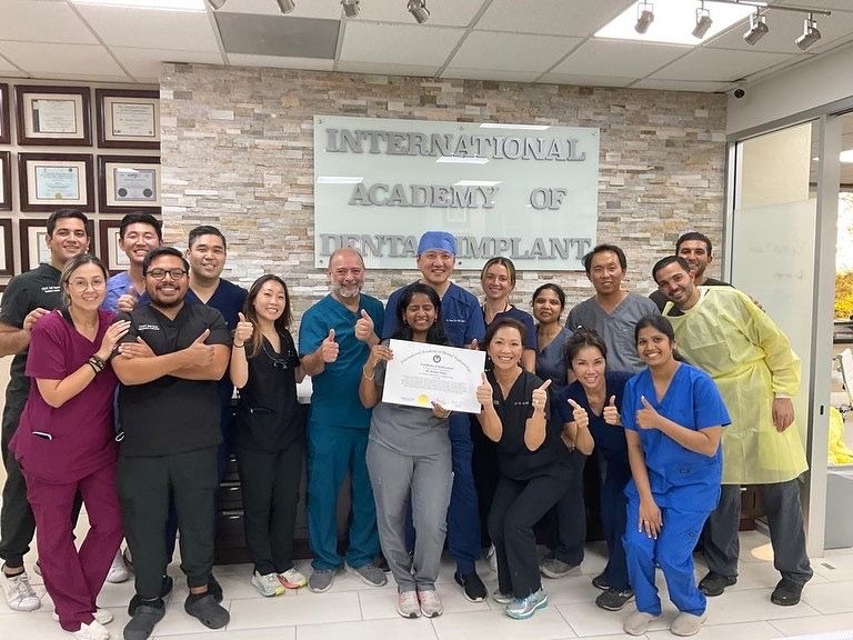 A group of people are posing for a picture in front of a sign that says international academy of dental implants.
