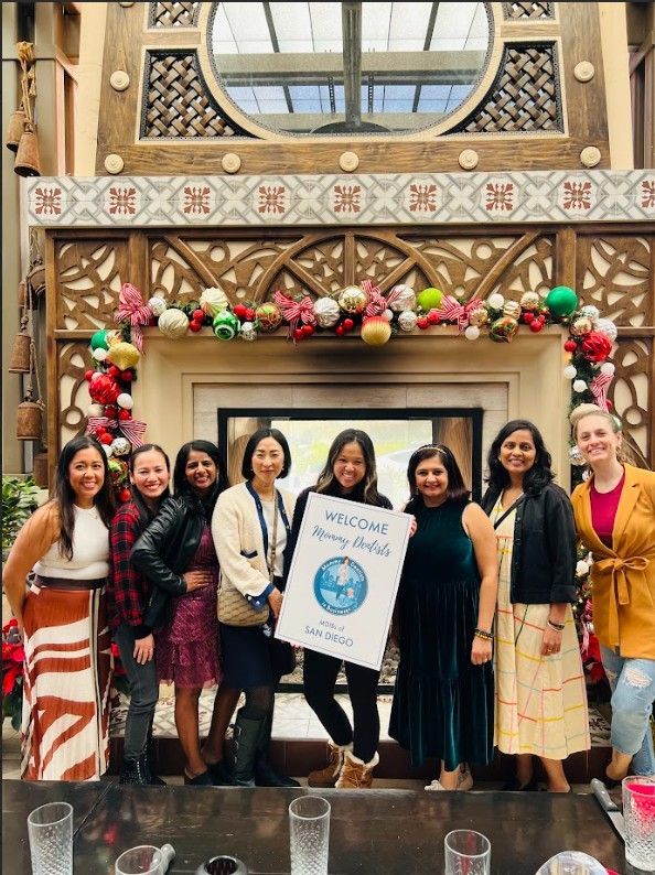 A group of women are posing for a picture in front of a fireplace.