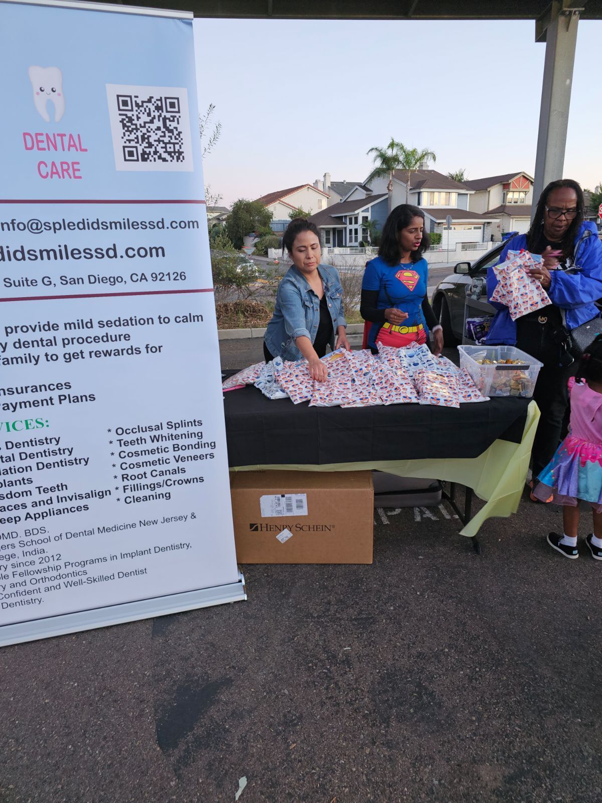 A group of people standing around a table with a sign that says dental care