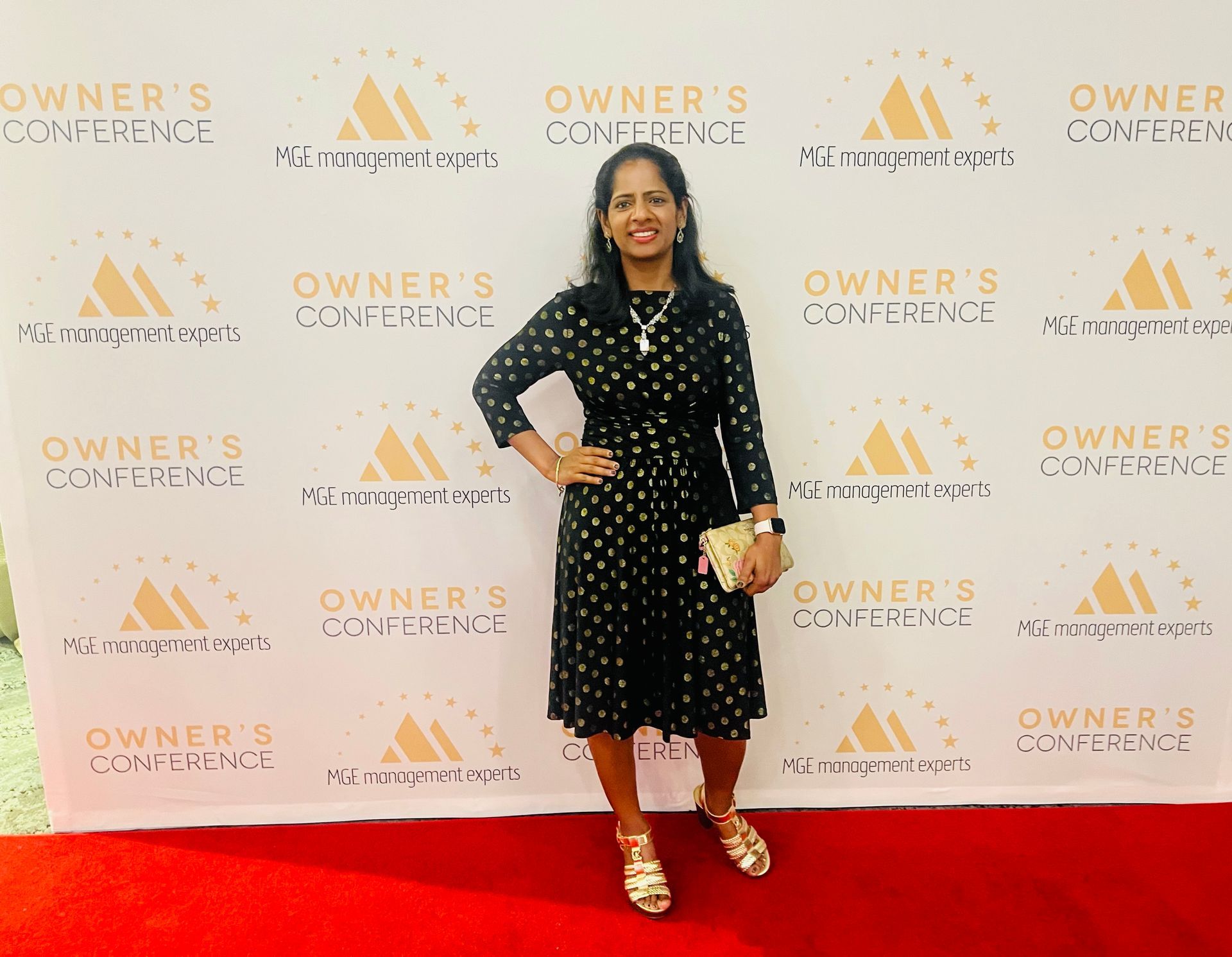 A woman is standing in front of a wall that says owner 's conference.