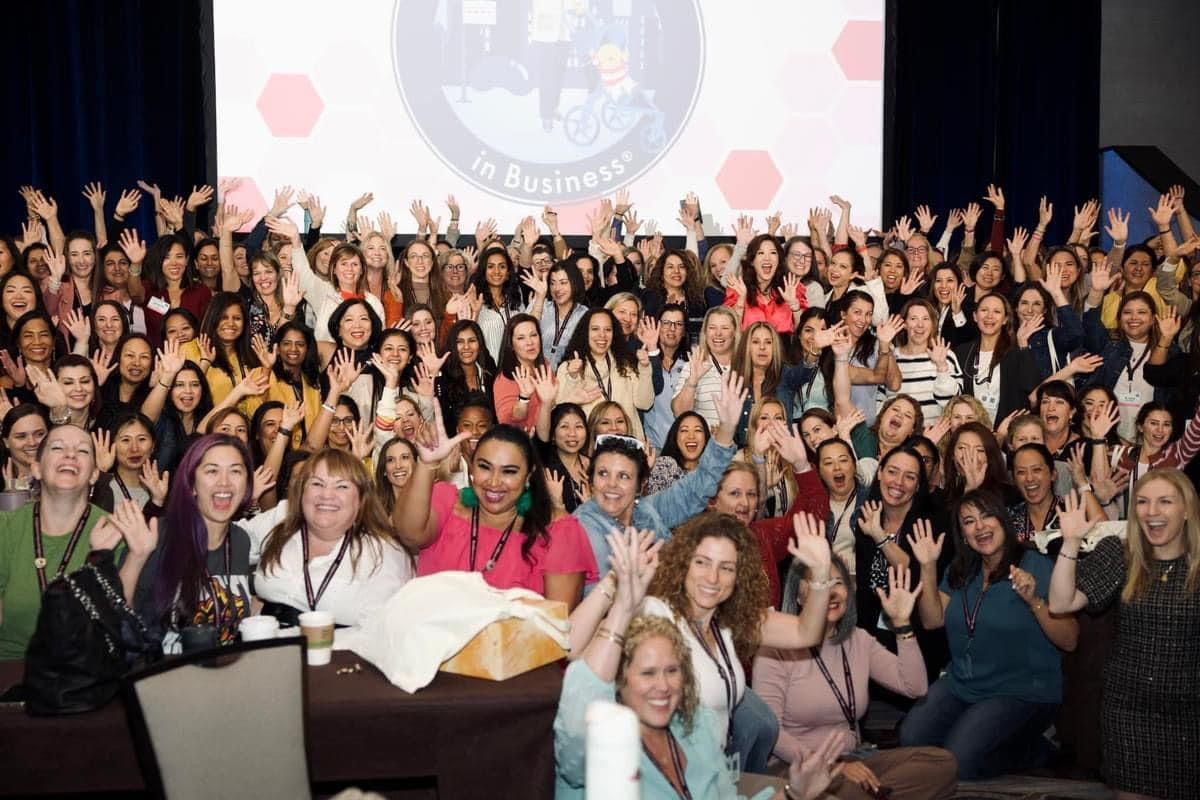 A large group of women are posing for a picture at a conference.