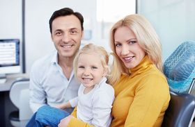 A family is sitting in a dental chair with a little girl