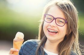 A young girl with braces is holding an ice cream cone