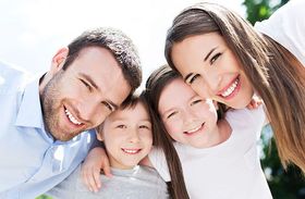 A family is posing for a picture together and smiling for the camera