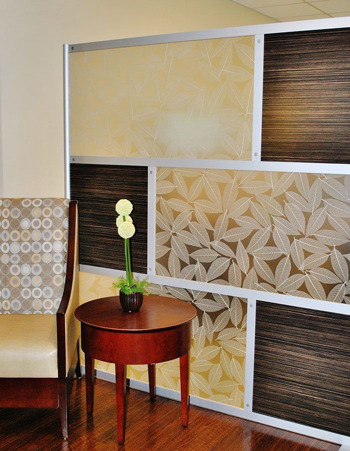 A room divider with patterned panels and a small table with a flower, next to a chair.