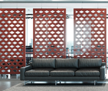 Three red diamond-patterned room dividers behind a black leather sofa in a modern office.