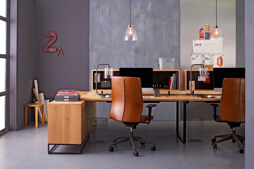 Office space with wood desks, leather chairs, and computers against gray and blue walls.