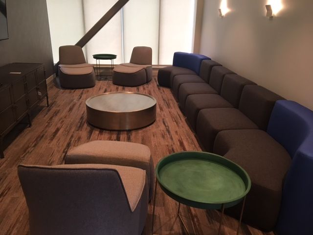 Modern lounge area with brown modular sofa, armchairs, coffee table, and green side tables.