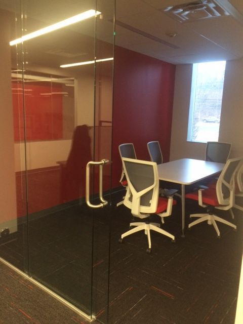 Conference room with a glass door, a table, and chairs. Red accent wall.