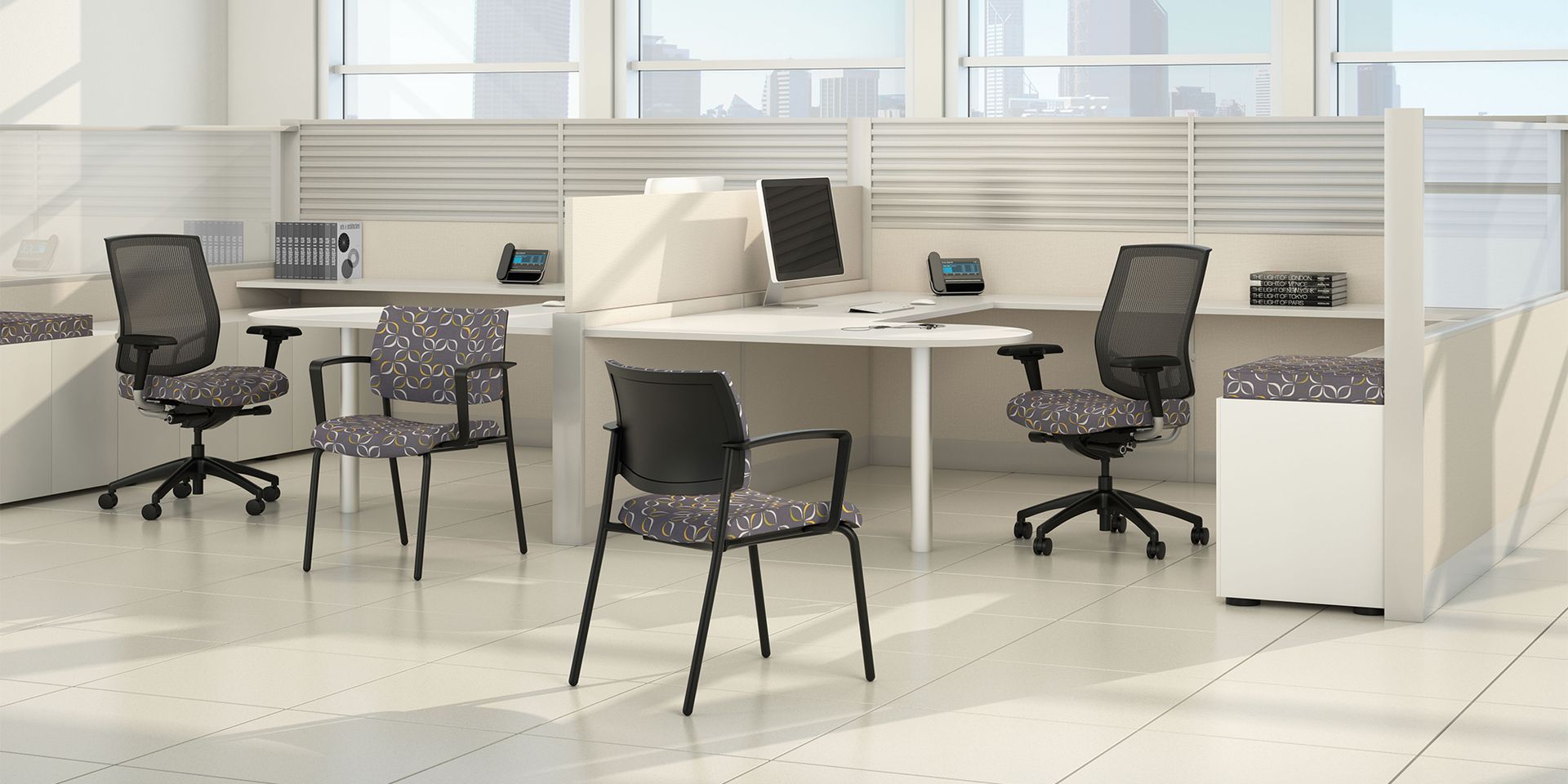 Office cubicles with desks, chairs, and computers. The space is white with large windows.