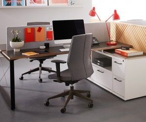 Office cubicle with a computer, gray office chair, and colorful desk accessories.