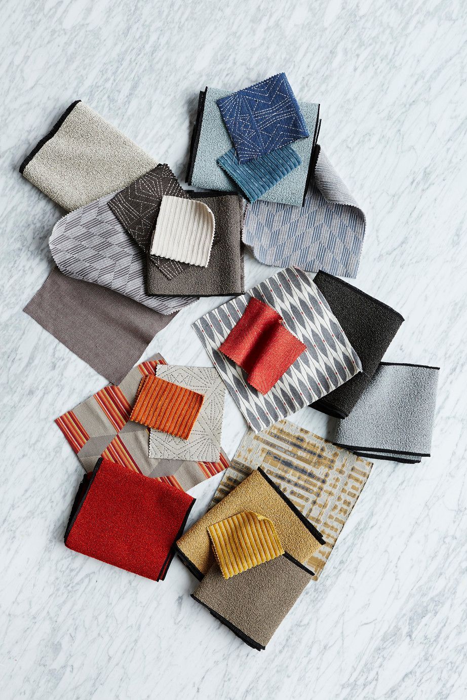 Pile of various textured fabric swatches in different colors against a light background.