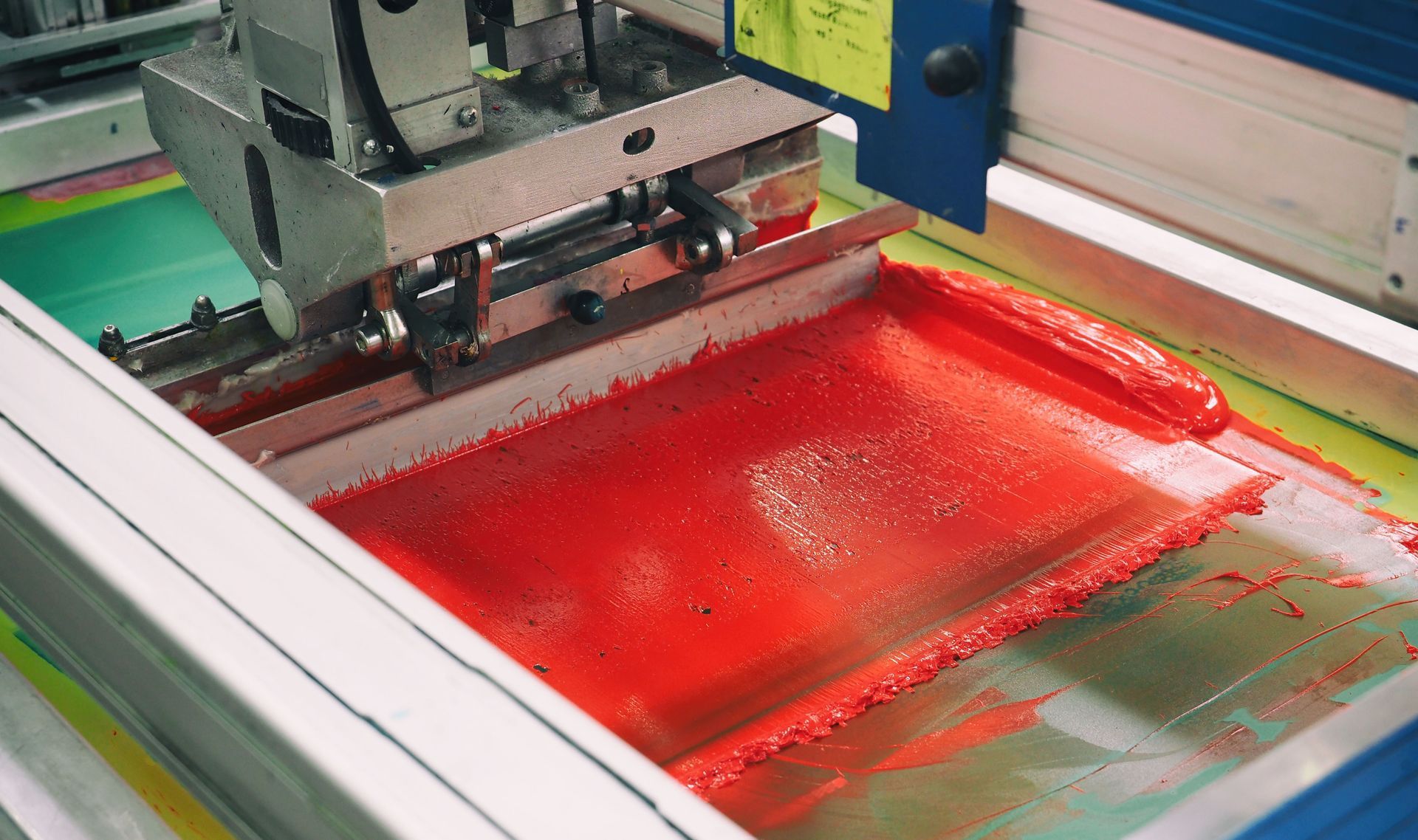 Screen printing machine applying red ink to a surface.