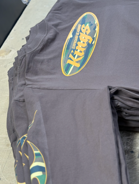 Stack of gray t-shirts with an oval Kings logo printed on them.
