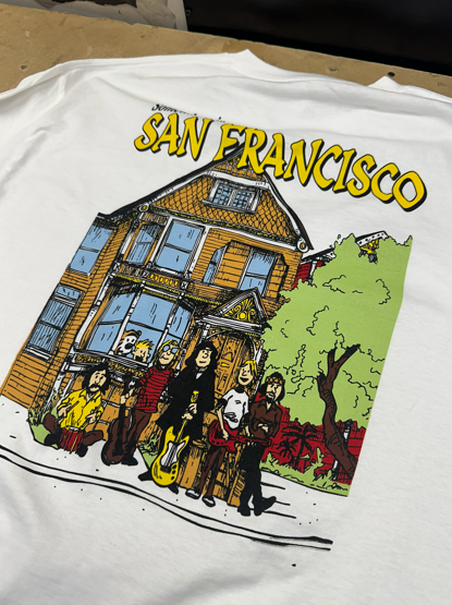 White t-shirt with a cartoon of a San Francisco house and a band, text 