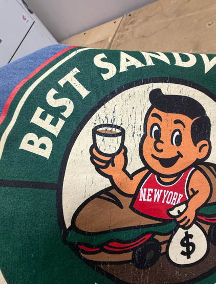 Logo of a cartoon boy holding coffee, on a sandwich. Text says 