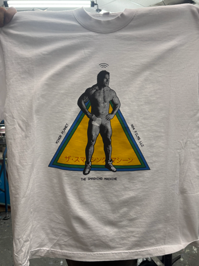 White t-shirt with a muscular figure inside a blue triangle on a gold background, text included.