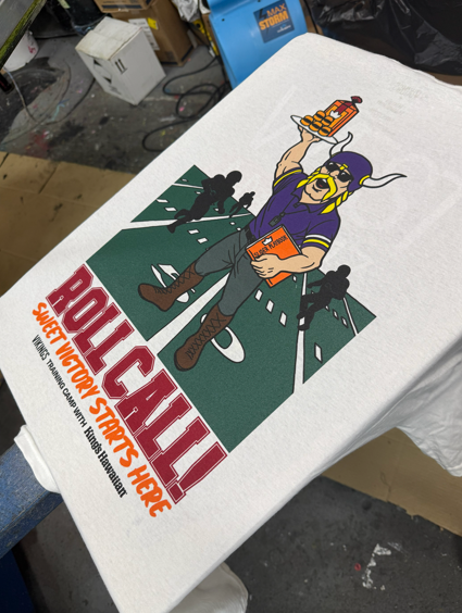 White t-shirt with a Viking mascot holding food over a football field with 