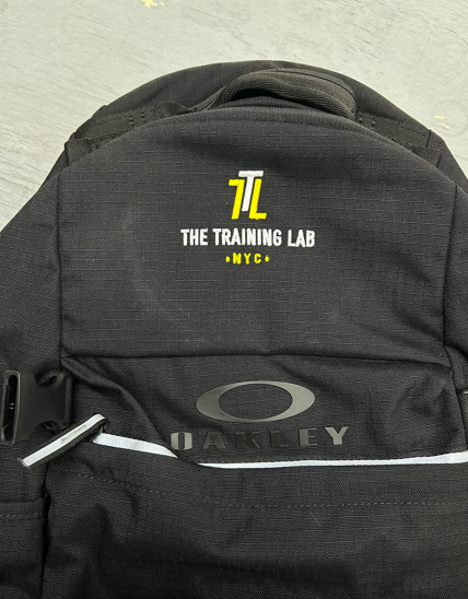 Black Oakley backpack with The Training Lab logo in yellow, over 