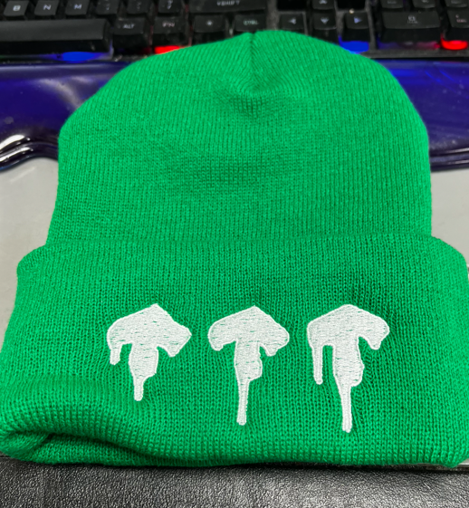 Green beanie with three white dripping shapes.