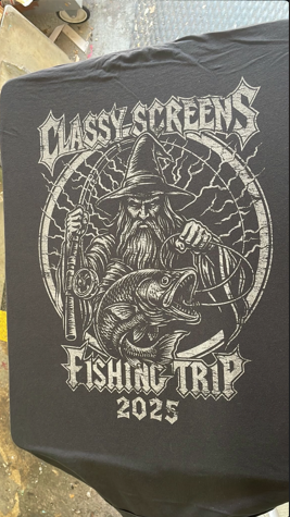 Black t-shirt with Classy Screens fishing trip graphic: wizard with fish, rod, and lightning, dated 2025.